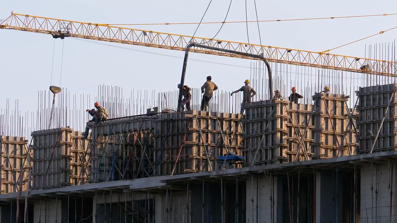 Crew working on concrete formwork with a crane overhead