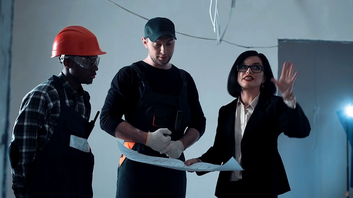 Three people reviewing a construction plan on site